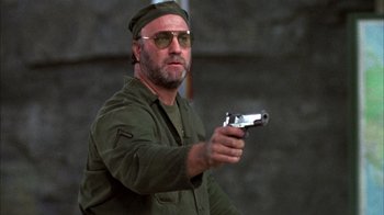 Movie still from “Day of the Dead” (1985), directed by George A. Romero – A man holding a gun while wearing sunglasses; Close Up shot, Low angle