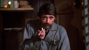 Movie still from “Day of the Dead” (1985), directed by George A. Romero – A man smoking a cigarette while sitting down in a room; Close Up shot, High angle