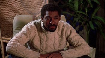 Movie still from “Day of the Dead” (1985), directed by George A. Romero – A man sitting in a chair wearing a white sweater; Medium shot, High angle