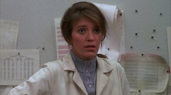 Movie still from “Day of the Dead” (1985), directed by George A. Romero – A woman wearing a lab coat in front of a wall; Close Up shot, Over the shoulder angle
