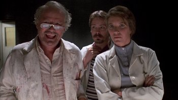 Movie still from “Day of the Dead” (1985), directed by George A. Romero – A group of people standing next to each other in a dark room; Medium shot, Low angle