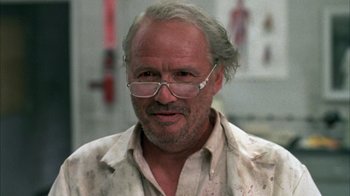 Movie still from “Day of the Dead” (1985), directed by George A. Romero – An older man wearing glasses and a lab coat; Close Up shot, Low angle