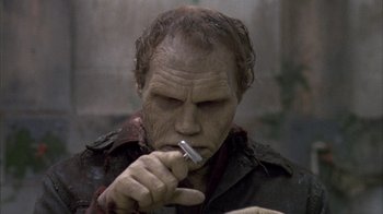 Movie still from “Day of the Dead” (1985), directed by George A. Romero – An old man is holding a cell phone in his hand; Close Up shot, Low angle