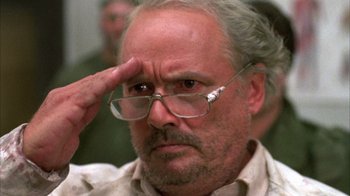 Movie still from “Day of the Dead” (1985), directed by George A. Romero – An older man wearing glasses and looking at the camera; Close Up shot, Low angle