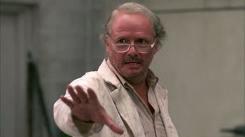 Movie still from “Day of the Dead” (1985), directed by George A. Romero – An older man with glasses is holding his hand out; Close Up shot, Low angle
