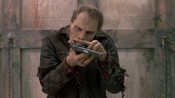 Movie still from “Day of the Dead” (1985), directed by George A. Romero – A man holding a cell phone in his hands; Medium shot, Low angle