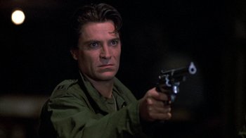 Movie still from “Day of the Dead” (1985), directed by George A. Romero – A man holding a gun while standing in the dark; Close Up shot, Low angle