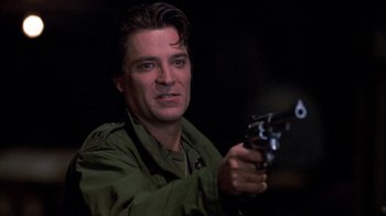 Movie still from “Day of the Dead” (1985), directed by George A. Romero – A man holding a gun while wearing a green jacket; Close Up shot, Low angle