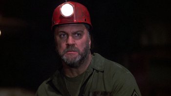 Movie still from “Day of the Dead” (1985), directed by George A. Romero – A man wearing a red hard hat with a light on top of his head; Close Up shot, Low angle