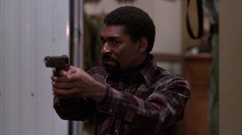 Movie still from “Day of the Dead” (1985), directed by George A. Romero – A man in a plaid shirt holding a gun in his hand; Medium shot, Low angle