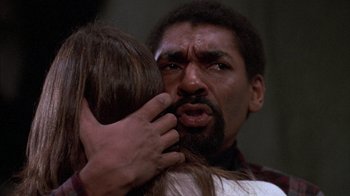 Movie still from “Day of the Dead” (1985), directed by George A. Romero – A man and a woman hug and kiss in front of a window; Close Up shot, Low angle