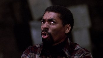 Movie still from “Day of the Dead” (1985), directed by George A. Romero – A man with a beard and a plaid shirt is making a funny face; Close Up shot, Low angle