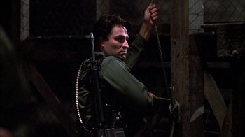 Movie still from “Day of the Dead” (1985), directed by George A. Romero – A man holding onto a rope with a gun in his hand; Medium shot, Low angle