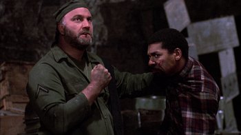Movie still from “Day of the Dead” (1985), directed by George A. Romero – Two men in green shirts one of them is holding a tie; Medium shot, Over the shoulder angle
