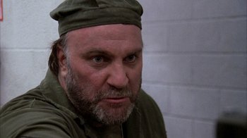 Movie still from “Day of the Dead” (1985), directed by George A. Romero – A person with a beard wearing a hat; Close Up shot, Over the shoulder angle