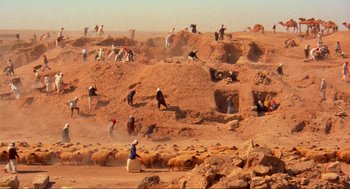 Movie still from “The Exorcist” (1973), directed by William Friedkin – A group of people on a dirt hill with a herd of sheep; Extreme Wide shot, High angle