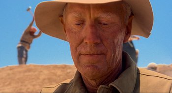 Movie still from “The Exorcist” (1973), directed by William Friedkin – An older man wearing a cowboy hat and looking sad; Close Up shot, Over the shoulder angle