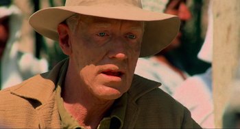 Movie still from “The Exorcist” (1973), directed by William Friedkin – An older man wearing a tan hat and a brown jacket; Close Up shot, Over the shoulder angle