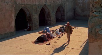 Movie still from “The Exorcist” (1973), directed by William Friedkin – A group of people kneeling down on the ground in front of a building; Wide shot, High angle