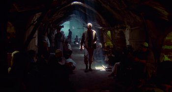 Movie still from “The Exorcist” (1973), directed by William Friedkin – A group of people sitting around in a tunnel; Wide shot, Low angle