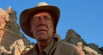 Movie still from “The Exorcist” (1973), directed by William Friedkin – An older man wearing a cowboy hat in front of some rocks; Close Up shot, Low angle