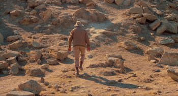 Movie still from “The Exorcist” (1973), directed by William Friedkin – A man walking on a dirt path in the desert; Wide shot, High angle