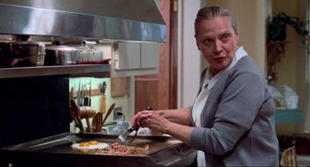 Movie still from “The Exorcist” (1973), directed by William Friedkin – A woman in a kitchen preparing food on a pan; Medium shot, Low angle