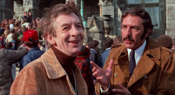 Movie still from “The Exorcist” (1973), directed by William Friedkin – A man in a brown jacket standing next to another man in a brown jacket; Medium shot, Low angle