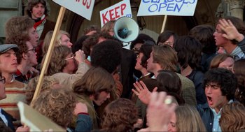 Movie still from “The Exorcist” (1973), directed by William Friedkin – A group of people standing around each other with signs; Medium shot, High angle