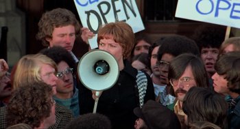 Movie still from “The Exorcist” (1973), directed by William Friedkin – A woman with a megaphone in front of a group of people; Medium shot, High angle
