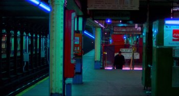 Movie still from “The Exorcist” (1973), directed by William Friedkin – A man sitting on a train platform next to a train station; Extreme Wide shot, High angle