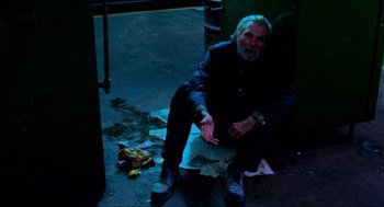 Movie still from “The Exorcist” (1973), directed by William Friedkin – An older man sitting on the ground in the dark; Medium shot, Low angle