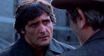 Movie still from “The Exorcist” (1973), directed by William Friedkin – A man with a beard and a hat talking to another man; Close Up shot, Over the shoulder angle