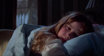 Movie still from “The Exorcist” (1973), directed by William Friedkin – A young girl laying in a bed with a blanket; Close Up shot, High angle