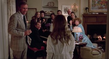 Movie still from “The Exorcist” (1973), directed by William Friedkin – A group of people gathered around a woman in a white dress; Medium shot, Over the shoulder angle