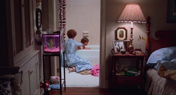 Movie still from “The Exorcist” (1973), directed by William Friedkin – A woman and a child sitting in a bath tub in a room; Wide shot, High angle