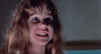 Movie still from “The Exorcist” (1973), directed by William Friedkin – A young girl with long hair and an evil look on her face; Close Up shot, High angle