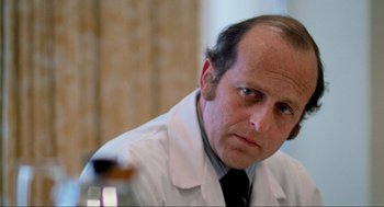 Movie still from “The Exorcist” (1973), directed by William Friedkin – A person wearing a white lab coat; Close Up shot, Over the shoulder angle