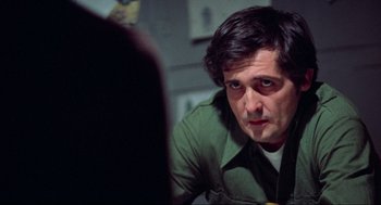 Movie still from “The Exorcist” (1973), directed by William Friedkin – A man in a green shirt is looking at a mirror; Close Up shot, Over the shoulder angle
