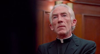 Movie still from “The Exorcist” (1973), directed by William Friedkin – An older man wearing a priest's outfit; Close Up shot, Low angle