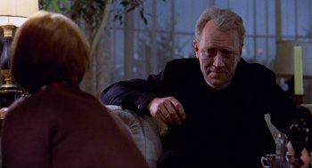 Movie still from “The Exorcist” (1973), directed by William Friedkin – An older man sitting on a couch looking at a woman; Medium shot, Over the shoulder angle