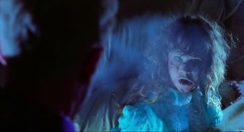 Movie still from “The Exorcist” (1973), directed by William Friedkin – A young girl in a blue dress is in a bed; Close Up shot, Over the shoulder angle