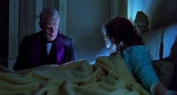 Movie still from “The Exorcist” (1973), directed by William Friedkin – A man and a woman are looking at a book; Medium shot, Low angle