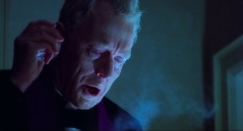 Movie still from “The Exorcist” (1973), directed by William Friedkin – An older man in a black suit is crying; Close Up shot, Low angle