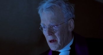 Movie still from “The Exorcist” (1973), directed by William Friedkin – An older man wearing a suit and glasses; Close Up shot, Over the shoulder angle