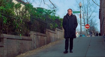 Movie still from “The Exorcist” (1973), directed by William Friedkin – A man standing on the side of the street; Medium shot, Low angle