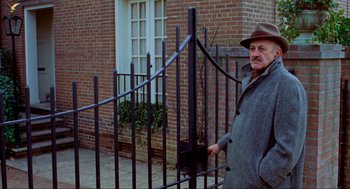 Movie still from “The Exorcist” (1973), directed by William Friedkin – A man standing next to an iron fence; Medium shot, Low angle