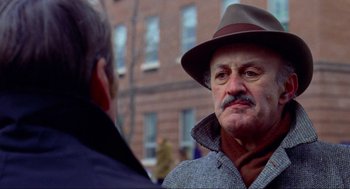 Movie still from “The Exorcist” (1973), directed by William Friedkin – A man in a hat talking to another man outside; Close Up shot, Over the shoulder angle