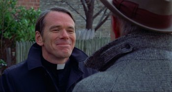 Movie still from “The Exorcist” (1973), directed by William Friedkin – A man wearing a priest's outfit talking to another man wearing a cowboy hat; Close Up shot, Over the shoulder angle