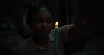 Movie still from “The Exorcist: Believer” (2023), directed by David Gordon Green – A woman holding a lit candle in a dark room; Close Up shot, Over the shoulder angle